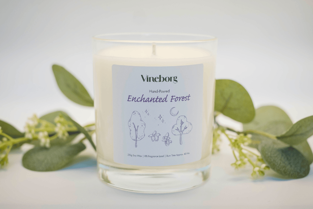 Vineborg Enchanted Forest candle with greenery on a light background