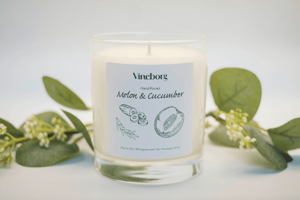 Vineborg candle labeled 'Melon & Cucumber' with green leaves in the background